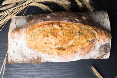 Taze ve lezzetli kepekli ekmek veya somun için sağlıklı beslenme arka plan siyah ahşap kesme tahtası üzerinde