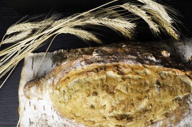 Taze ve lezzetli kepekli ekmek veya somun için sağlıklı beslenme arka plan siyah ahşap kesme tahtası üzerinde