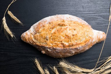 Taze ve lezzetli kepekli ekmek veya somun için sağlıklı beslenme arka plan siyah ahşap kesme tahtası üzerinde