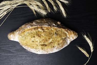 Taze ve lezzetli kepekli ekmek veya somun için sağlıklı beslenme arka plan siyah ahşap kesme tahtası üzerinde