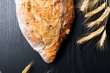 Taze ve lezzetli kepekli ekmek veya somun için sağlıklı beslenme arka plan siyah ahşap kesme tahtası üzerinde