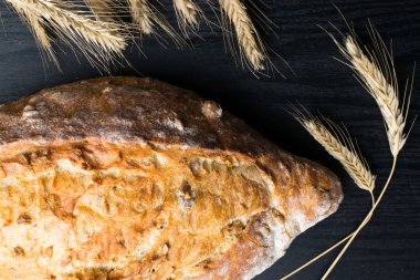 Taze ve lezzetli kepekli ekmek veya somun için sağlıklı beslenme arka plan siyah ahşap kesme tahtası üzerinde