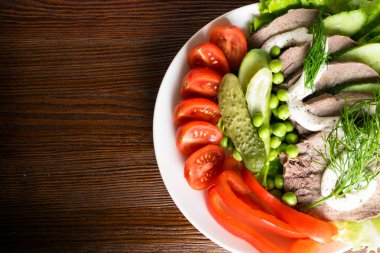 haşlanmış dil ile sebze domates biber salatalık marul bezelye ahşap masanın üzerine mayonezli dilimler.