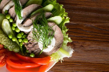 haşlanmış dil ile sebze domates biber salatalık marul bezelye ahşap masanın üzerine mayonezli dilimler.