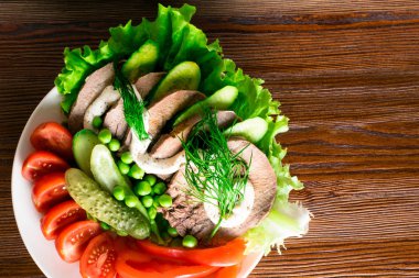 haşlanmış dil ile sebze domates biber salatalık marul bezelye ahşap masanın üzerine mayonezli dilimler.