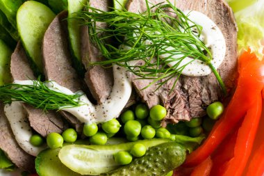 haşlanmış dil ile sebze domates biber salatalık marul bezelye ahşap masanın üzerine mayonezli dilimler.