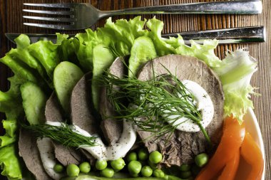 haşlanmış dil ile sebze domates biber salatalık marul bezelye ahşap masanın üzerine mayonezli dilimler.