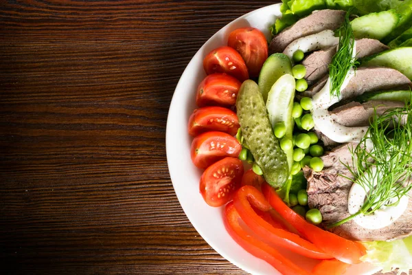 haşlanmış dil ile sebze domates biber salatalık marul bezelye ahşap masanın üzerine mayonezli dilimler.