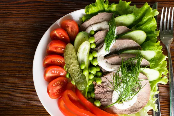 haşlanmış dil ile sebze domates biber salatalık marul bezelye ahşap masanın üzerine mayonezli dilimler.