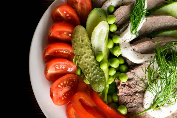 haşlanmış dil ile sebze domates biber salatalık marul bezelye ahşap masanın üzerine mayonezli dilimler.