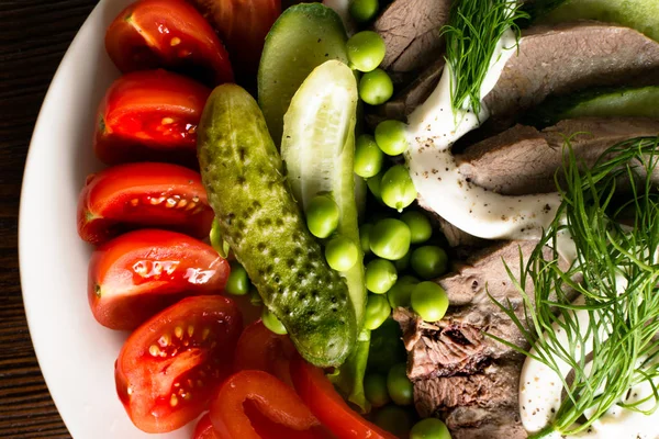 haşlanmış dil ile sebze domates biber salatalık marul bezelye ahşap masanın üzerine mayonezli dilimler.