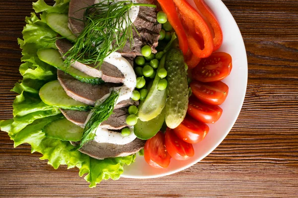 haşlanmış dil ile sebze domates biber salatalık marul bezelye ahşap masanın üzerine mayonezli dilimler.