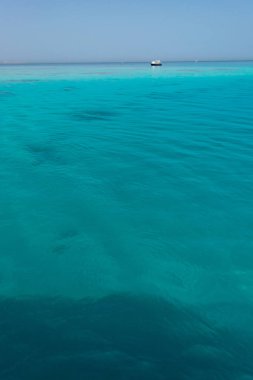 Uzaktan red Sea'deki/daki ufuk ile arka planda sahil boyunca yelken yat