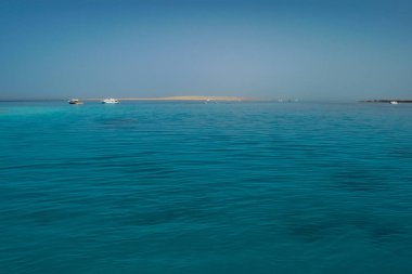 Uzaktan red Sea'deki/daki ufuk ile arka planda sahil boyunca yelken yat