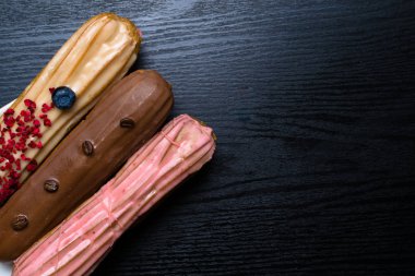 Fransız geleneksel C'eclair, ahududu, yaban mersini, krem, kahve fasulye siyah arka plan üzerine dekore