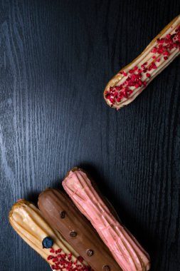 Fransız geleneksel C'eclair, ahududu, yaban mersini, krem, kahve fasulye siyah arka plan üzerine dekore