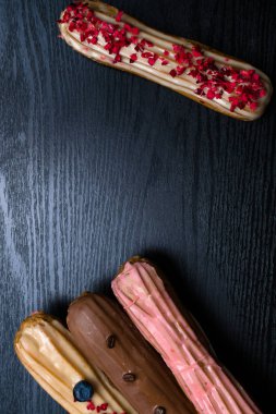 Fransız geleneksel C'eclair, ahududu, yaban mersini, krem, kahve fasulye siyah arka plan üzerine dekore