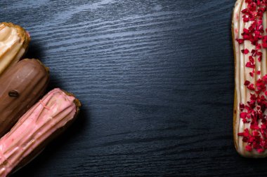 Fransız geleneksel C'eclair, ahududu, yaban mersini, krem, kahve fasulye siyah arka plan üzerine dekore