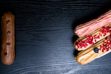 Fransız geleneksel C'eclair, ahududu, yaban mersini, krem, kahve fasulye siyah arka plan üzerine dekore