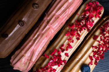 Fransız geleneksel C'eclair, ahududu, yaban mersini, krem, kahve fasulye siyah arka plan üzerine dekore