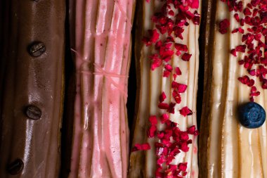 Fransız geleneksel C'eclair, ahududu, yaban mersini, krem, kahve fasulye siyah arka plan üzerine dekore