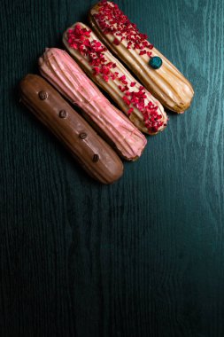 Fransız geleneksel C'eclair, ahududu, yaban mersini, krem, kahve fasulye siyah arka plan üzerine dekore