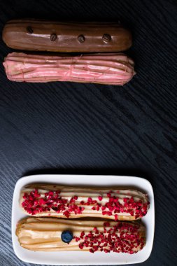 kahve çekirdekleri, yaban mersini, siyah ahşap masa üzerinde ahududu ile lezzetli renkli eklerleri