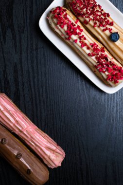 kahve çekirdekleri, yaban mersini, siyah ahşap masa üzerinde ahududu ile lezzetli renkli eklerleri