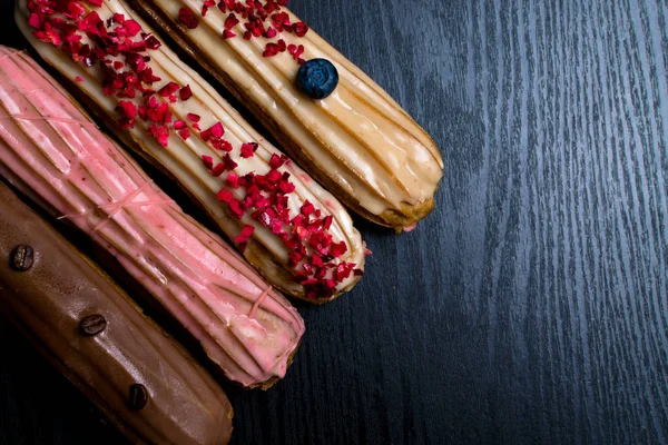 stock image French traditional eclair, decorated with raspberry, blueberry,cream and coffee beans on black background