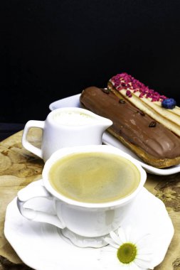 taze kahve, krema ve kahve çekirdekleri, papatya sürahi ile ahşap siyah plaka.