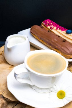 taze kahve, krema ve kahve çekirdekleri, papatya sürahi ile ahşap siyah plaka.