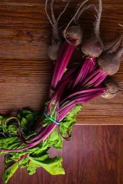 Kırmızı organik grup pancar ile yaylı yeşil yapraklar, ahşap arka plan üzerinde bırakır. Detoks. Seçici odak