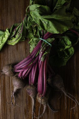 Kırmızı organik grup pancar ile yaylı yeşil yapraklar, ahşap arka plan üzerinde bırakır. Detoks