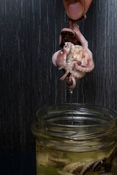 Preserves small octopus in a glass jar with olive oil. Health delicatessen food.
