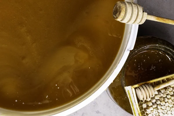 Med ve sklenici a velký kbelík, honeycomb a dřevěnou tyčí — Stock fotografie