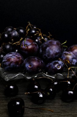Erik, üzüm, kiraz ahşap masa, siyah arka plan üzerinde ile natürmort. Sağlıklı beslenme. Vegan gıda