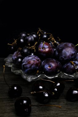 Erik, üzüm, kiraz ahşap masa, siyah arka plan üzerinde ile natürmort. Sağlıklı beslenme. Vegan gıda