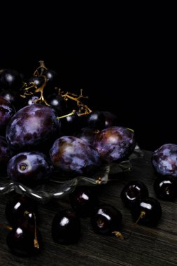 Erik, üzüm, kiraz ahşap masa, siyah arka plan üzerinde ile natürmort. Sağlıklı beslenme. Vegan gıda