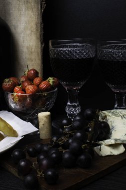 derin yağda kızartılmış kalamar halkaları kotletpane çilek, üzüm, ahşap arka plan üzerinde kırmızı şarap ve mavi peynir ile. Romantik kavramı