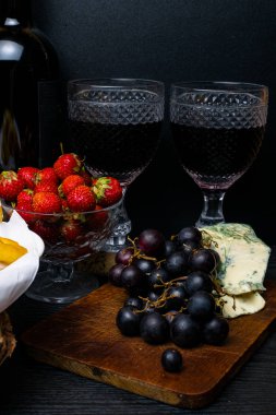 derin yağda kızartılmış kalamar halkaları kotletpane çilek, üzüm, ahşap arka plan üzerinde kırmızı şarap ve mavi peynir ile. Romantik kavramı