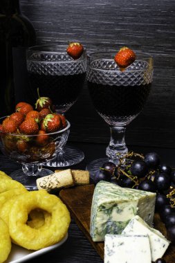 derin yağda kızartılmış kalamar halkaları kotletpane çilek, üzüm, ahşap arka plan üzerinde kırmızı şarap ve mavi peynir ile. Romantik kavramı