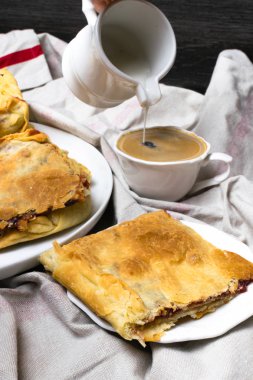 Kiraz, elmalı turta beyaz bir tabak ve bir fincan kahve, bir dilim krema ile sürahi