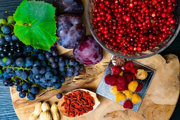 resveratrol, üzüm, Erik, goji, fıstık, kızılcık, çikolata, siyah ahşap arka plan, gıdalar sağlıklı bir kahvaltı - taze meyveler, raspberrys ile zengin besin fındık meyve