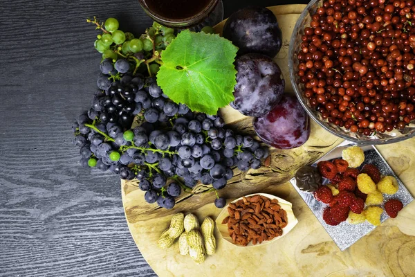 resveratrol, üzüm, Erik, goji, fıstık, kızılcık, çikolata, siyah ahşap arka plan, gıdalar sağlıklı bir kahvaltı - taze meyveler, raspberrys ile zengin besin fındık meyve