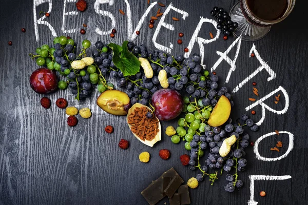 yiyecek zengin resveratrol, üzüm, Erik, goji, fıstık, kızılcık, raspberrys koyu çikolata, siyah ahşap zemin üzerine kırmızı şarap