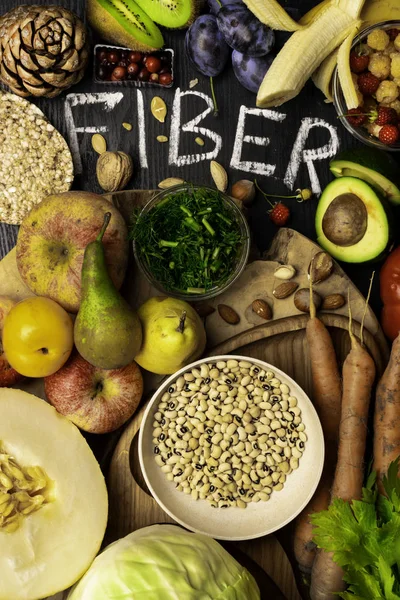Foods rich in fiber as rye galette , wheat bran, beans , almonds, seed, pears, plum bananas, cranberry, raspberries, pistachios, red pepper kiwi walnuts melon celery carrot Wooden table as background