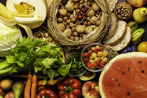 Foods rich in fiber as rye galette , bread, watermeon, wheat bran, beans , almonds, seed, pears, plum bananas, cranberry, raspberries, pistachios, red pepper kiwi walnuts melon celery carrot Wooden table as background