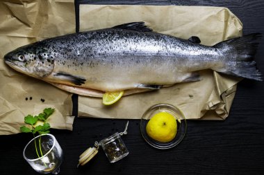 Çiğ somon maydanoz otlar limon dilimleri, rustik koyu arka plan üzerinde baharatlar ile. Balık pişirme için hazırlanıyor. Sağlıklı gıda kavramı. Üstten görünüm