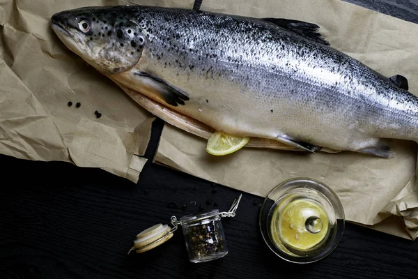 Fresh raw salmon red fish isolated on a black background with lemon and black pepper in glass jar. Flat lay. Top view, omega 3 source