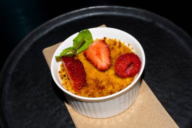 Creme brulee - geleneksel seramik beyaz kase çilek ahududu üzerinde üstte caramelised şekerli vanilya krem tatlı Fransız ve nane yaprağı